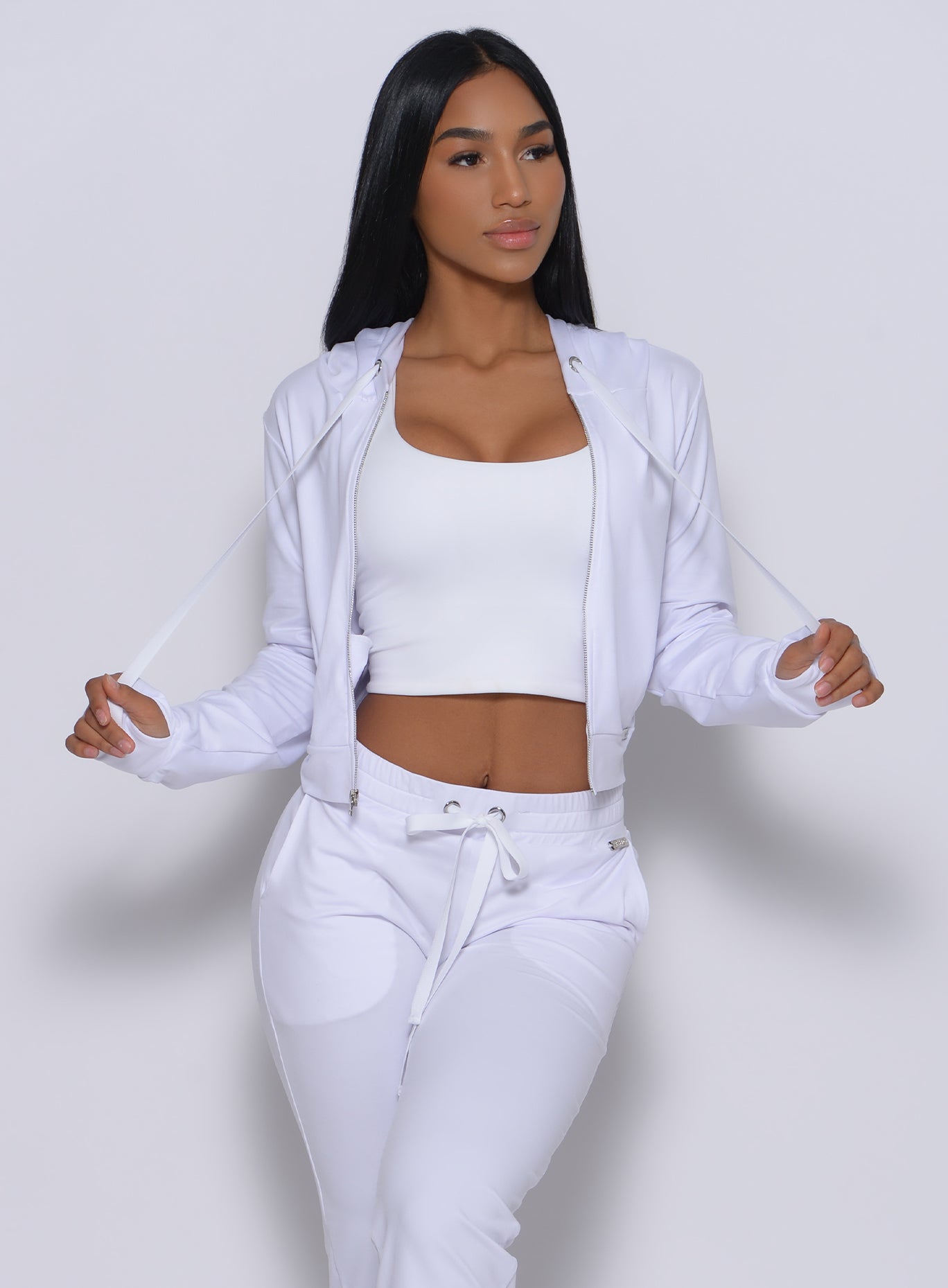 Front profile view of a model in our white signature jacket and a matching leggings 