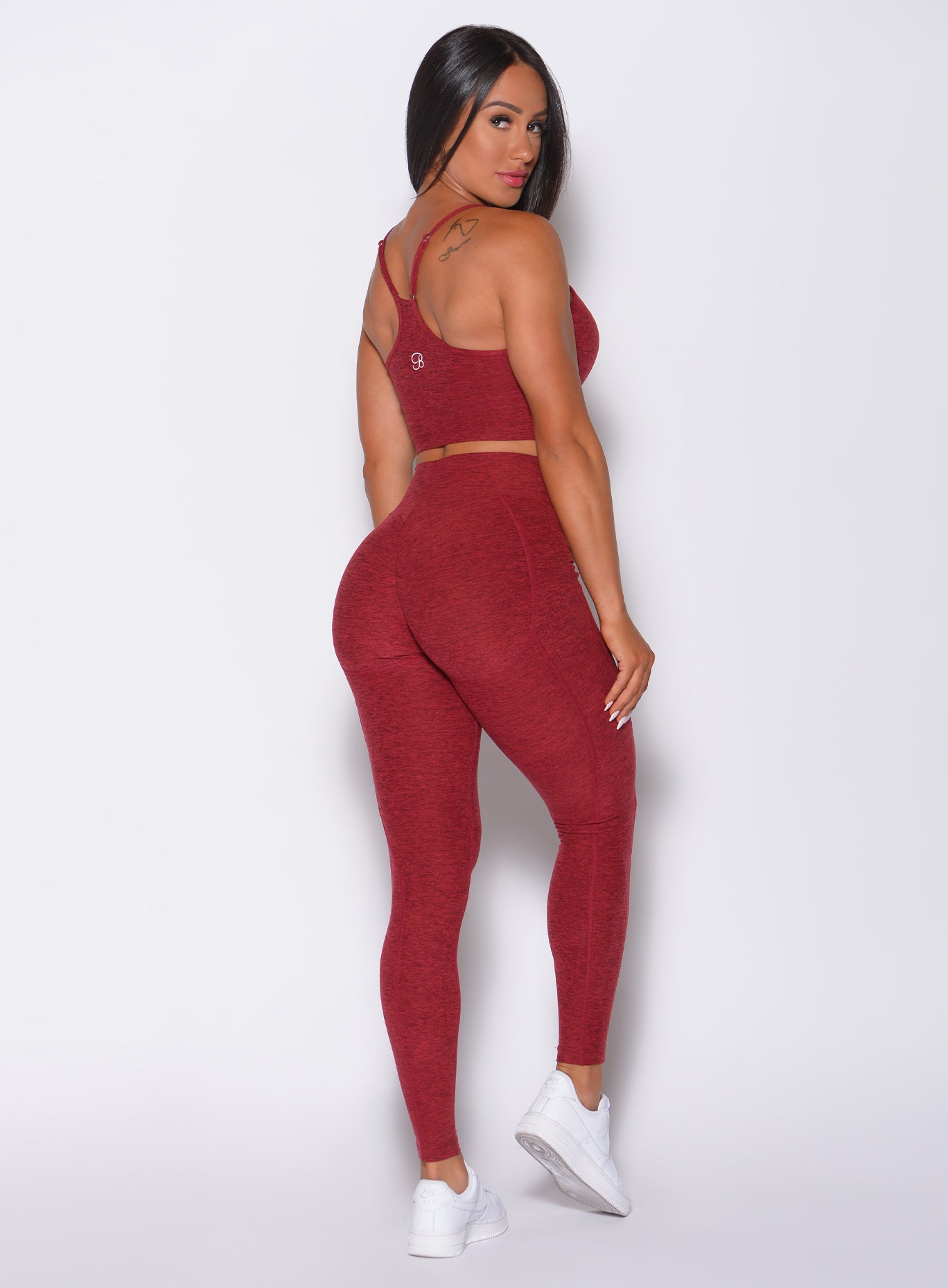 Back profile view of a model in our uplift pocket leggings in red rose color and a matching bra 