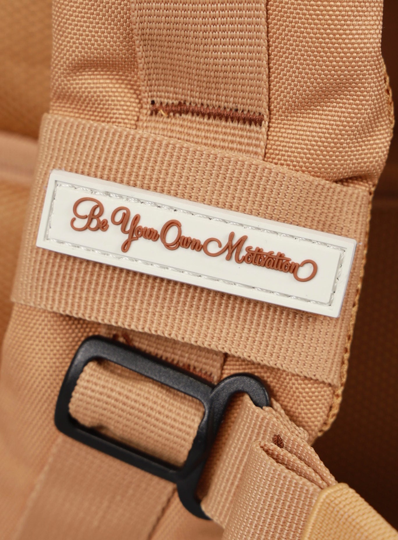 A photo depicting the be your own motivation mini patch on the strap of the   25L Backpack Bombshell Sportswear in Caramel color