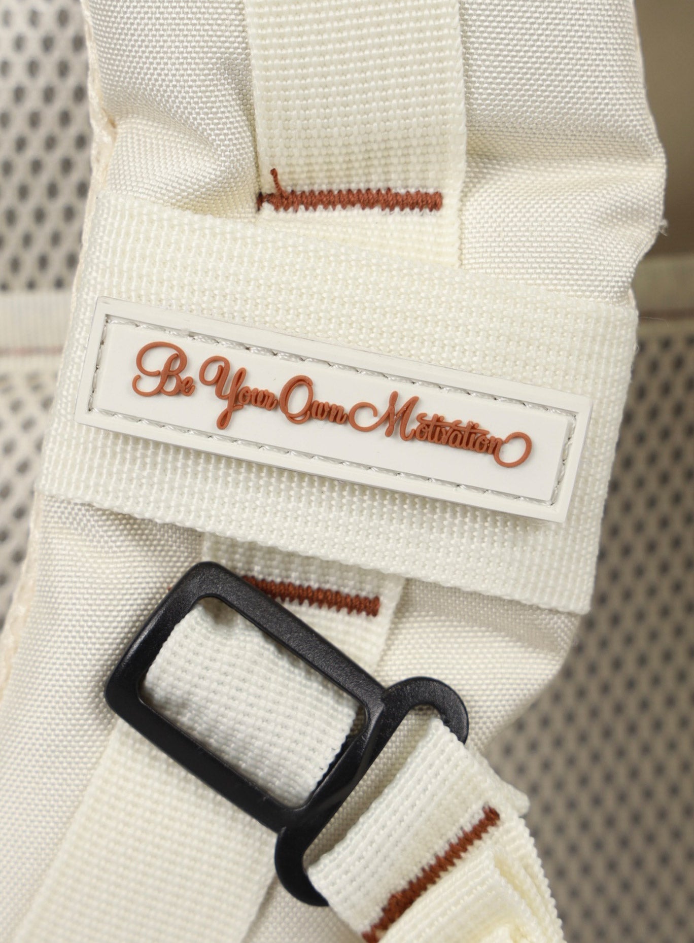 A photo depicting the be your own motivation mini patch on the strap of the   25L Backpack Bombshell Sportswear in Crème color
