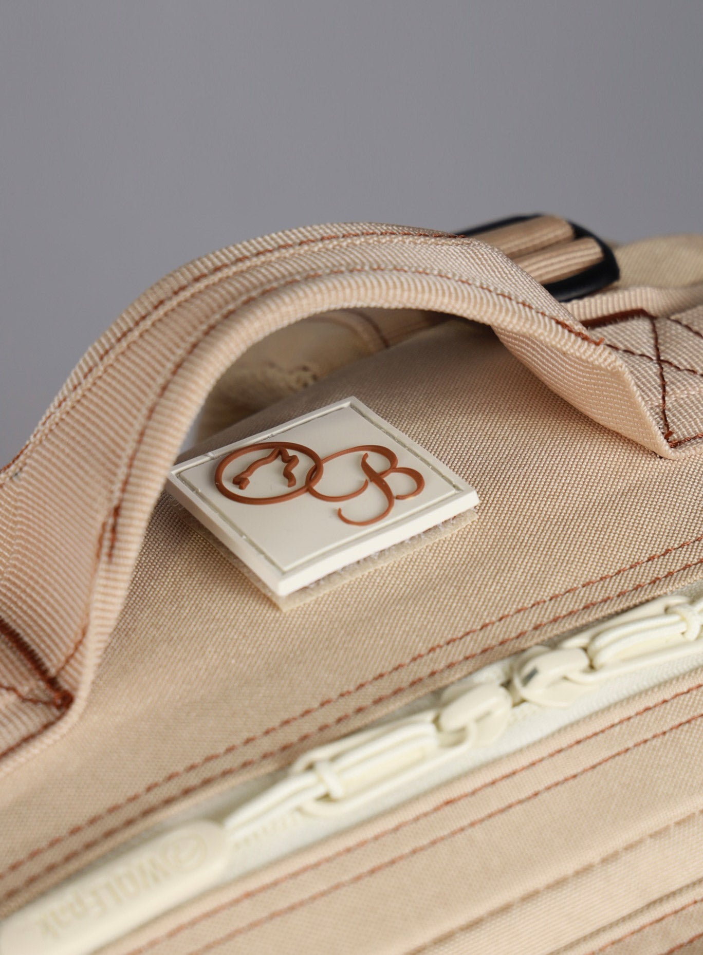 top side view of the Bombshell Sportswear X WOLFpak logo on the  25L Backpack Bombshell Sportswear in Latte color