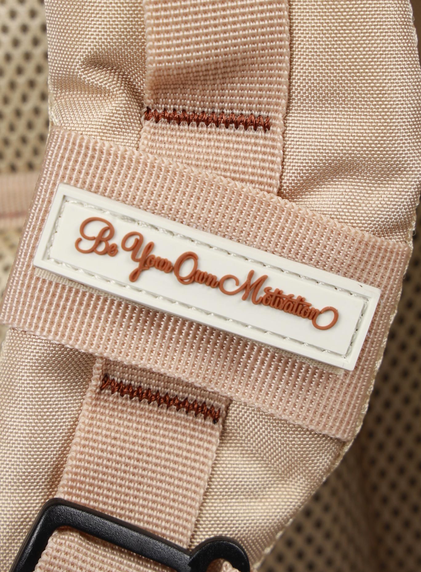 A photo depicting the be your own motivation mini patch on the strap of the  25L Backpack Bombshell Sportswear in Latte color