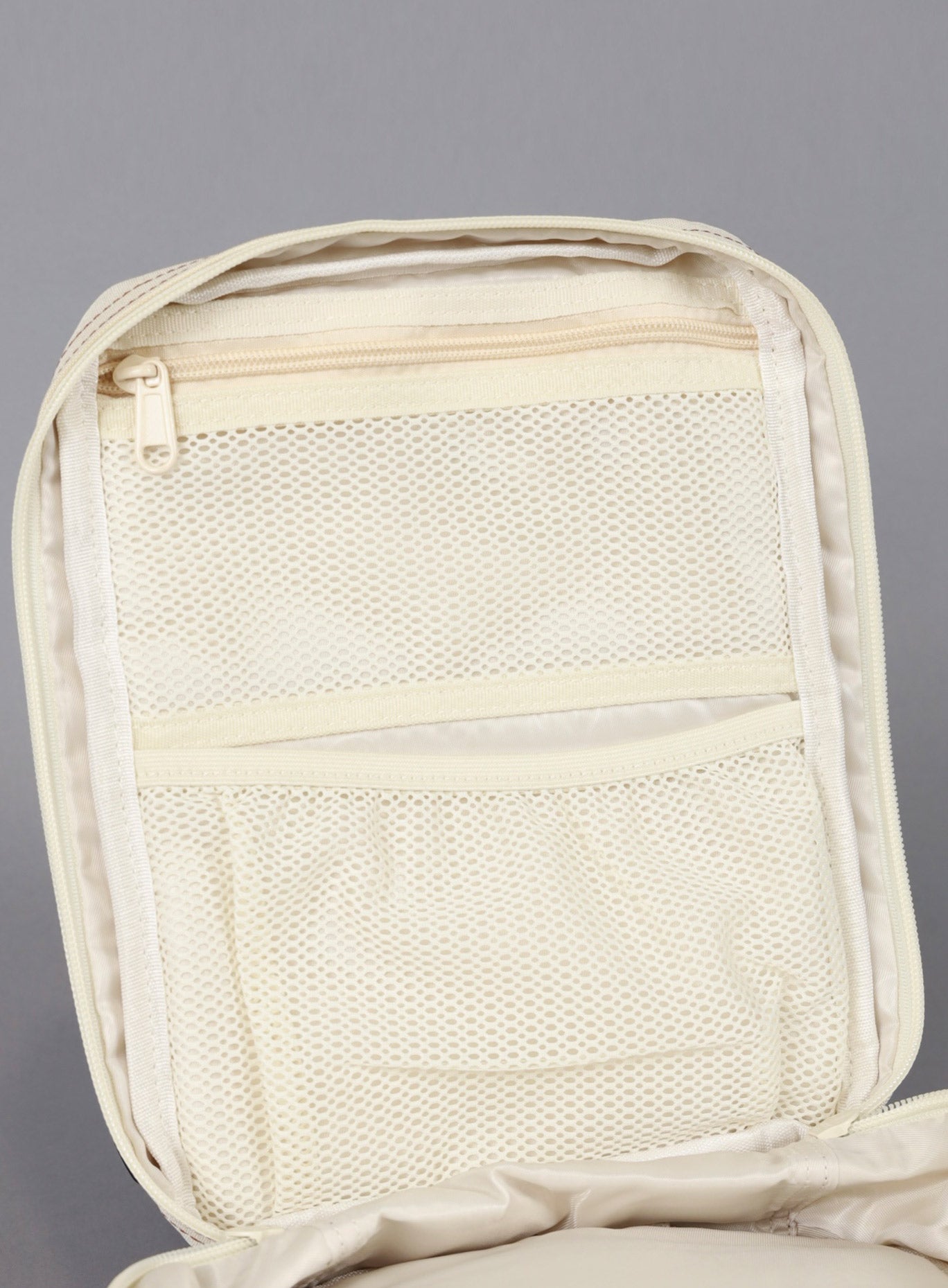 A unzipped picture of the the 9L Backpack Mini Bombshell Sportswear in Crème color showing the mesh compartments