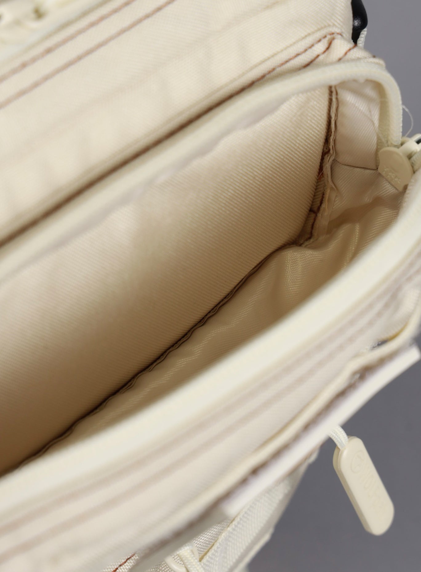 An image showcasing the top most compartment on the the 9L Backpack Mini Bombshell Sportswear in Crème color unzipped