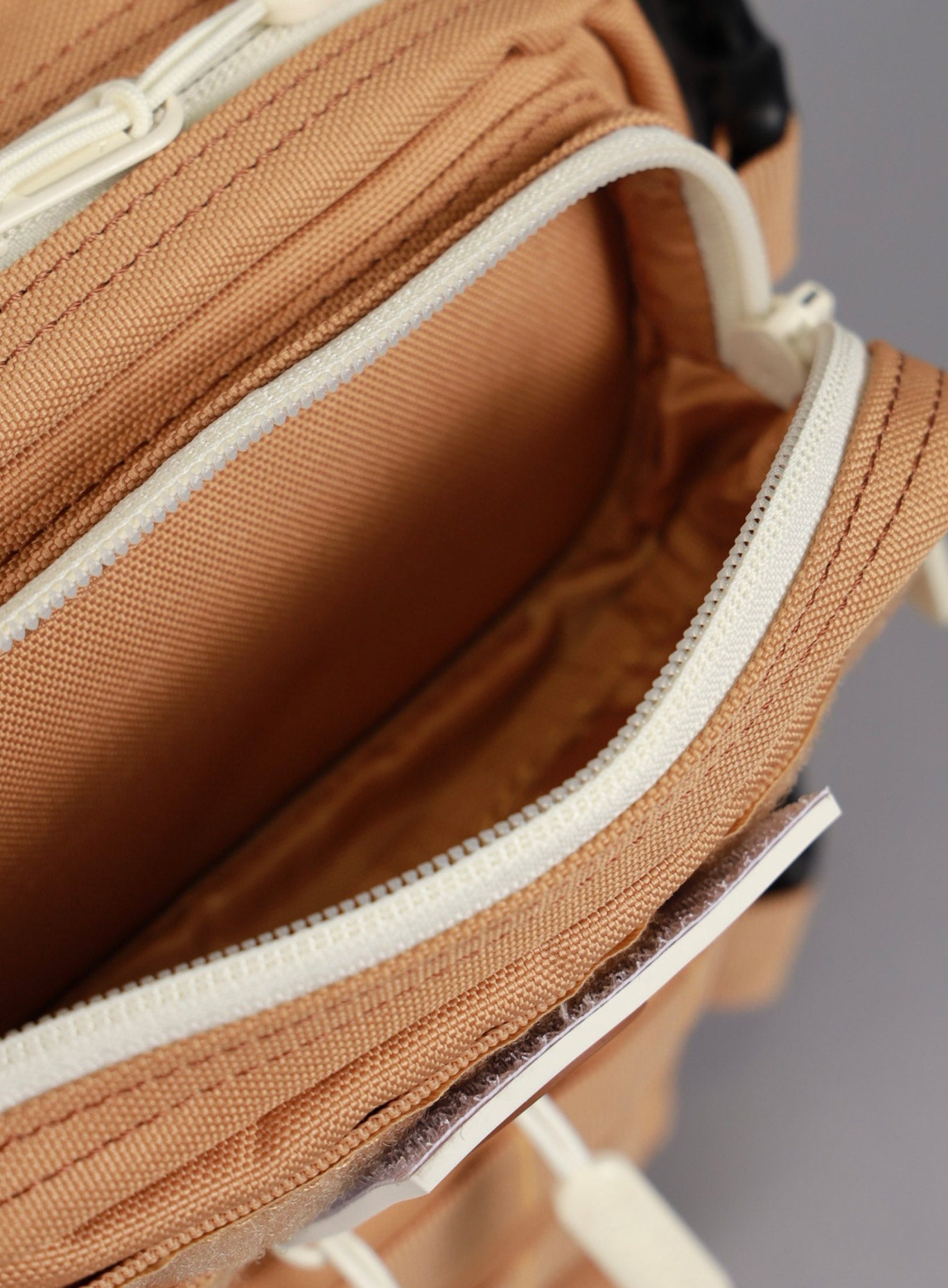 An image showcasing the top most compartment on the the 9L Backpack Mini Bombshell Sportswear in Caramel color unzipped