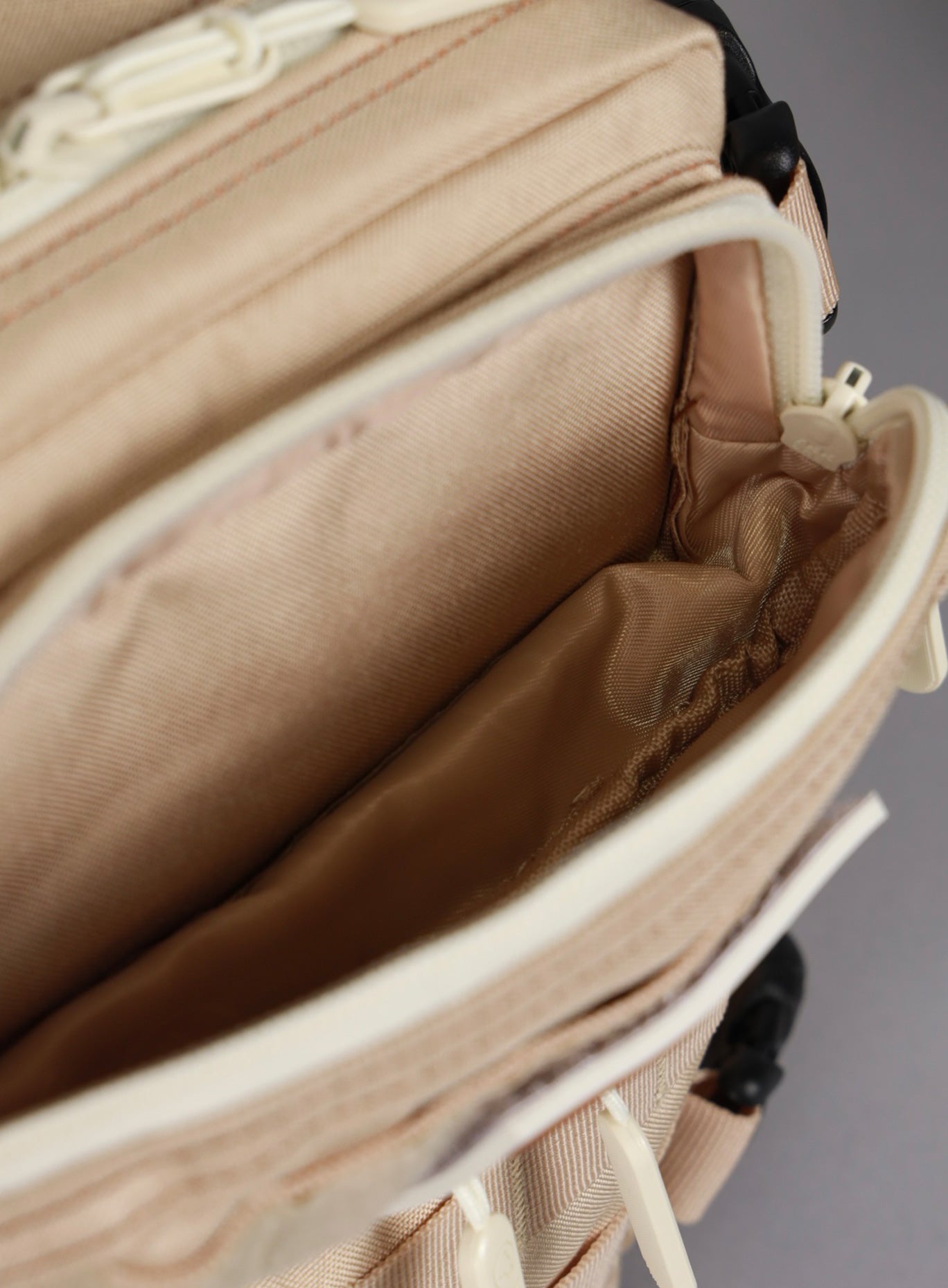 An image showing the uppermost compartment of the 9L Mini Bombshell Sportswear Latte backpack unzipped