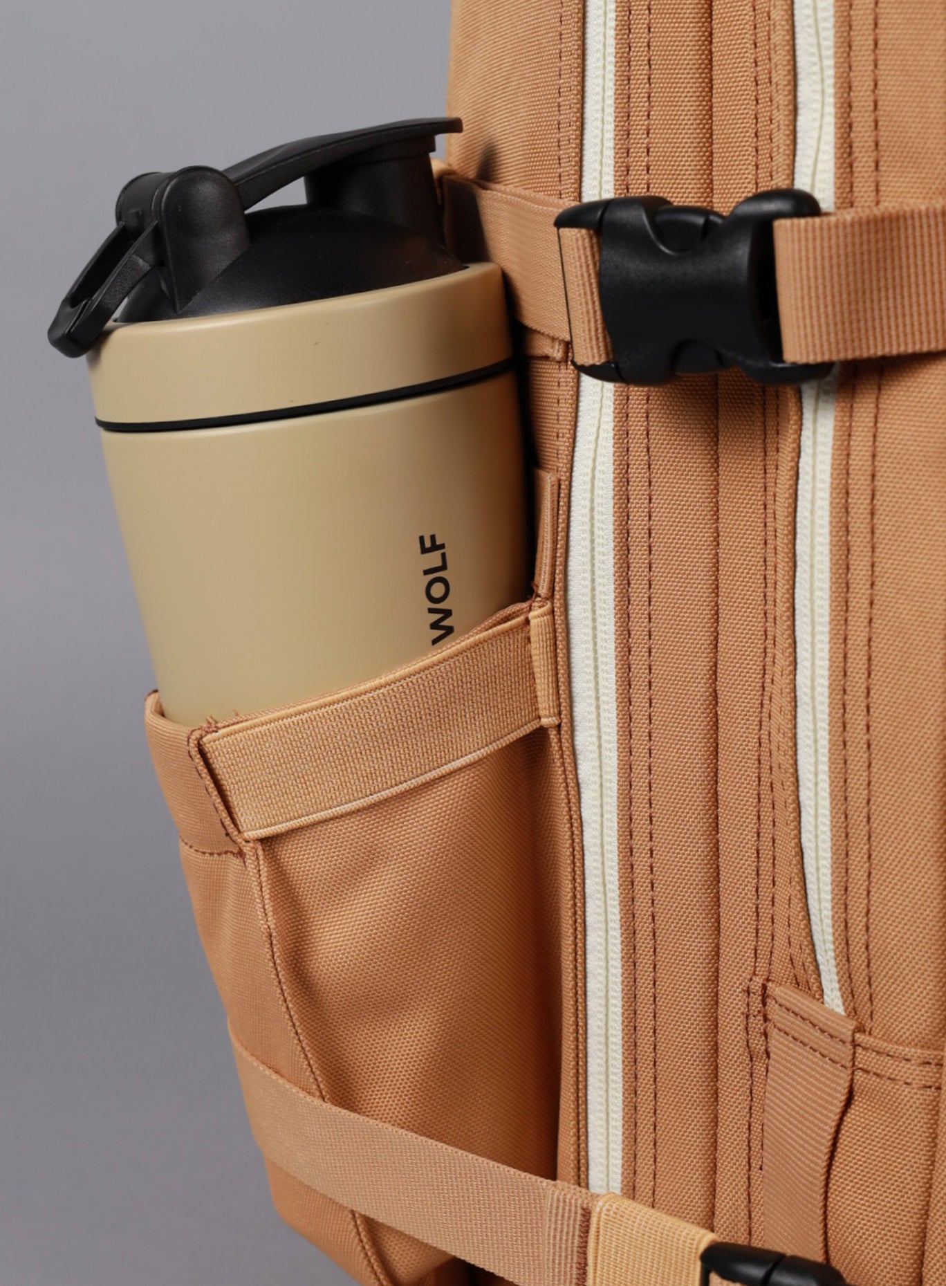 A photo showing the side of  25L Backpack Bombshell Sportswear in Caramel color with a bottle 