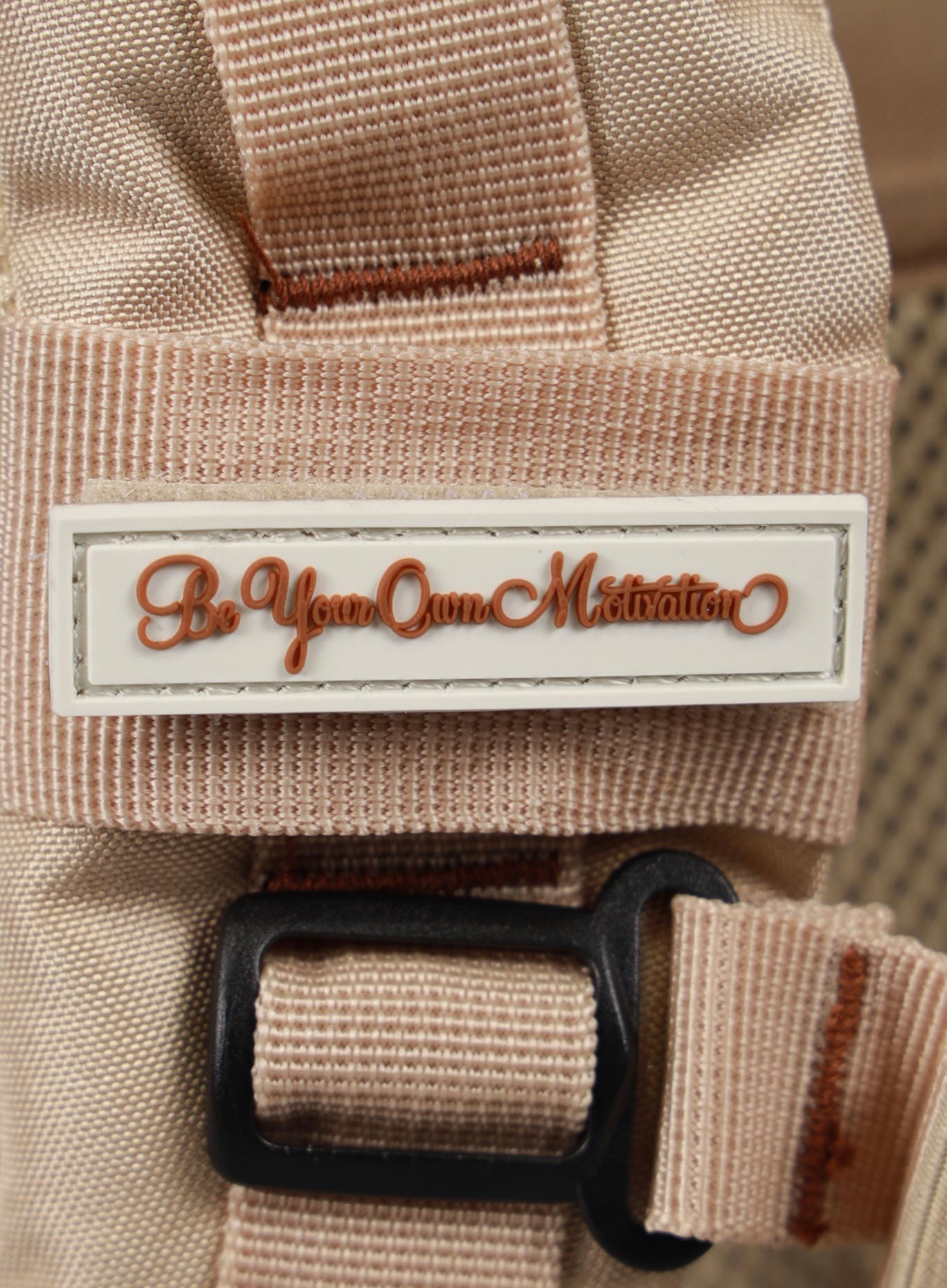 A photo depicting the be your own motivation mini patch on the strap of the 35L Bombshell Sportswear backpack in Latte color