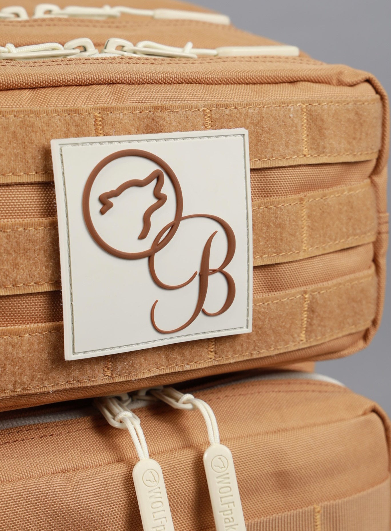 A detailed view of the Bombshell X WOLFpak logo featured on the 35L Bombshell Sportswear backpack in Caramel color