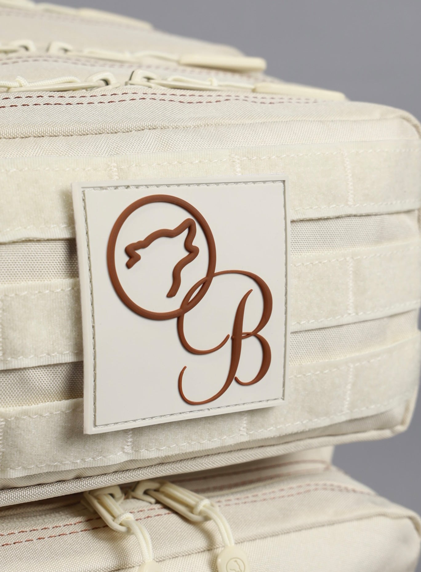 A detailed view of the Bombshell X WOLFpak logo featured on the 35L Bombshell Sportswear backpack in  Crème color