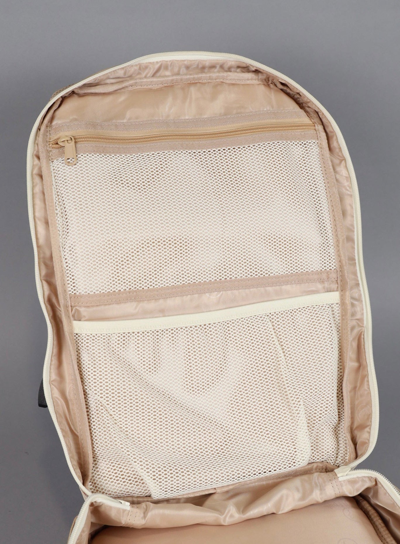 picture of the backpack showing the inner compartment with mesh pockets from wolfpak in latte color 
