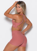  left side view of a model facing to her left wearing our Ace Sports Bra and the matching shorts in Sedona Clay color