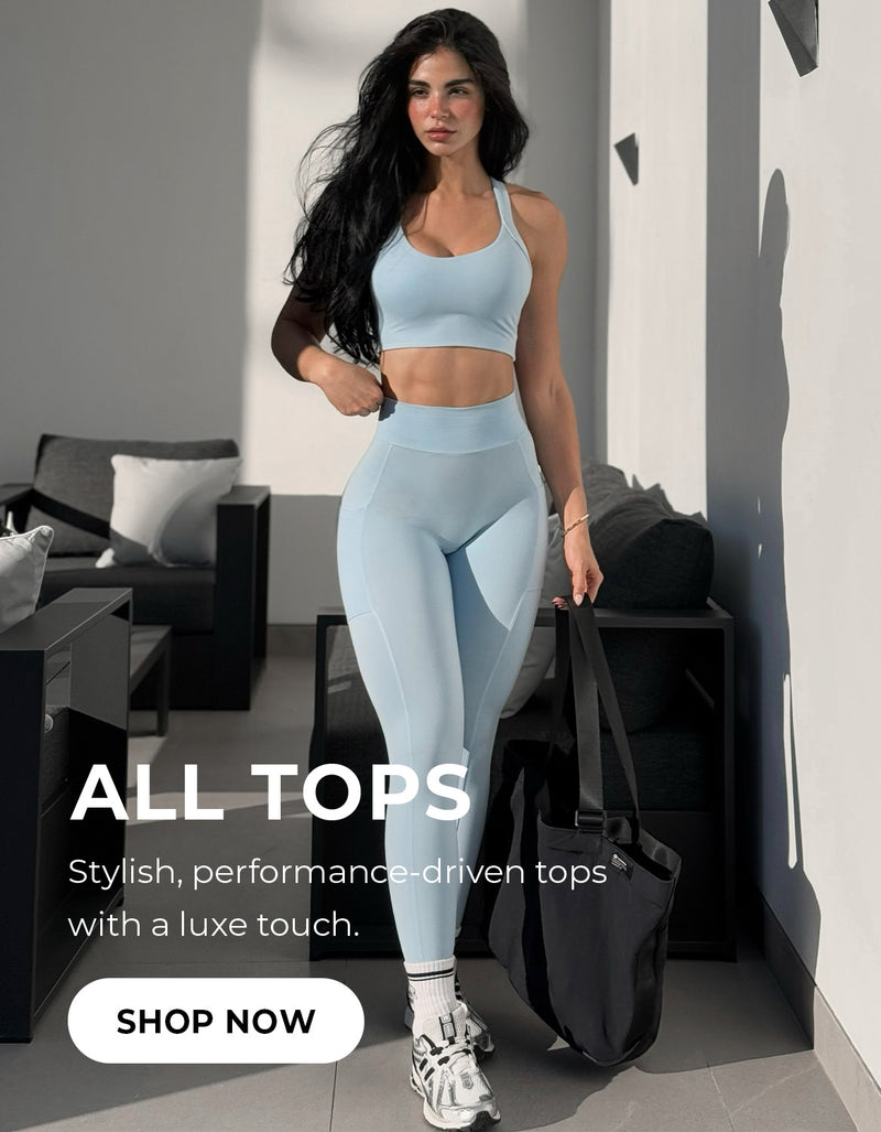 Model in blue sports bra and leggings looking forward near grey wall. Text reads, ALL TOPS stylish, performance-driven tops with a luxe touch SHOP NOW