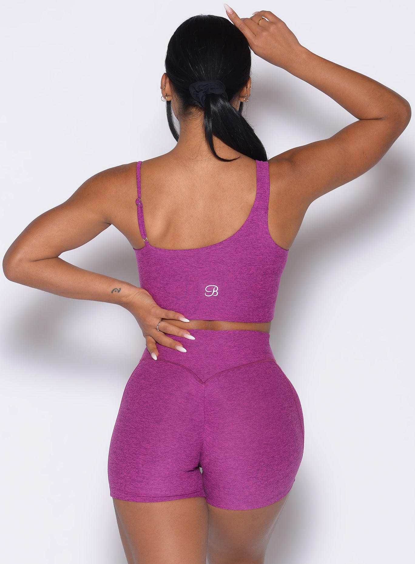 back profile of a model wearing the Asymmetrical Slit Bra and the matching Tiny Waist Shorts in Bright Plum color
