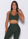 Front profile view of a model wearing our backless bra in hunter green along with the matching high waisted leggings 