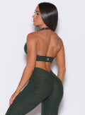 Back profile view of a model wearing our backless bra in hunter green along with the matching leggings 