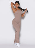 Front profile view of a model facing left and holding her hair wearing the Bombshell Bunny Bodysuit in Clay color. 