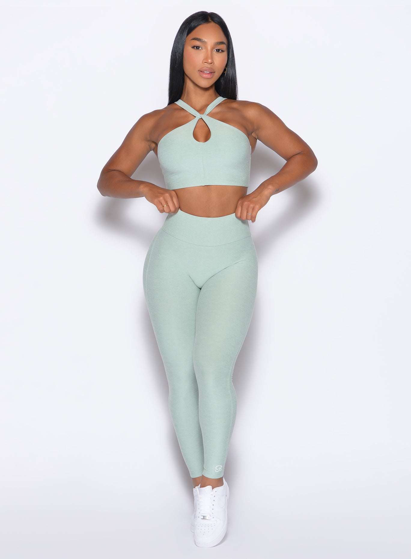 front profile view of our model adjusting the waistband wearing the Bombshell Bunny Leggings in soft aloe color