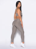 right side profile view of our model looking over her shoulder wearing the Bombshell Bunny Leggings in smoked taupe color