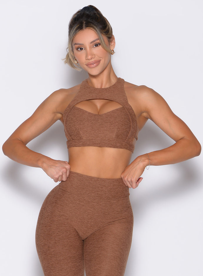 front profile view of a model with both hands on the waistband of the leggings wearing the Powerhouse bra in Coffee Bean color