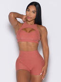 front profile view of a model with one hand on her thigh wearing the Powerhouse bra in Georgia Peach color