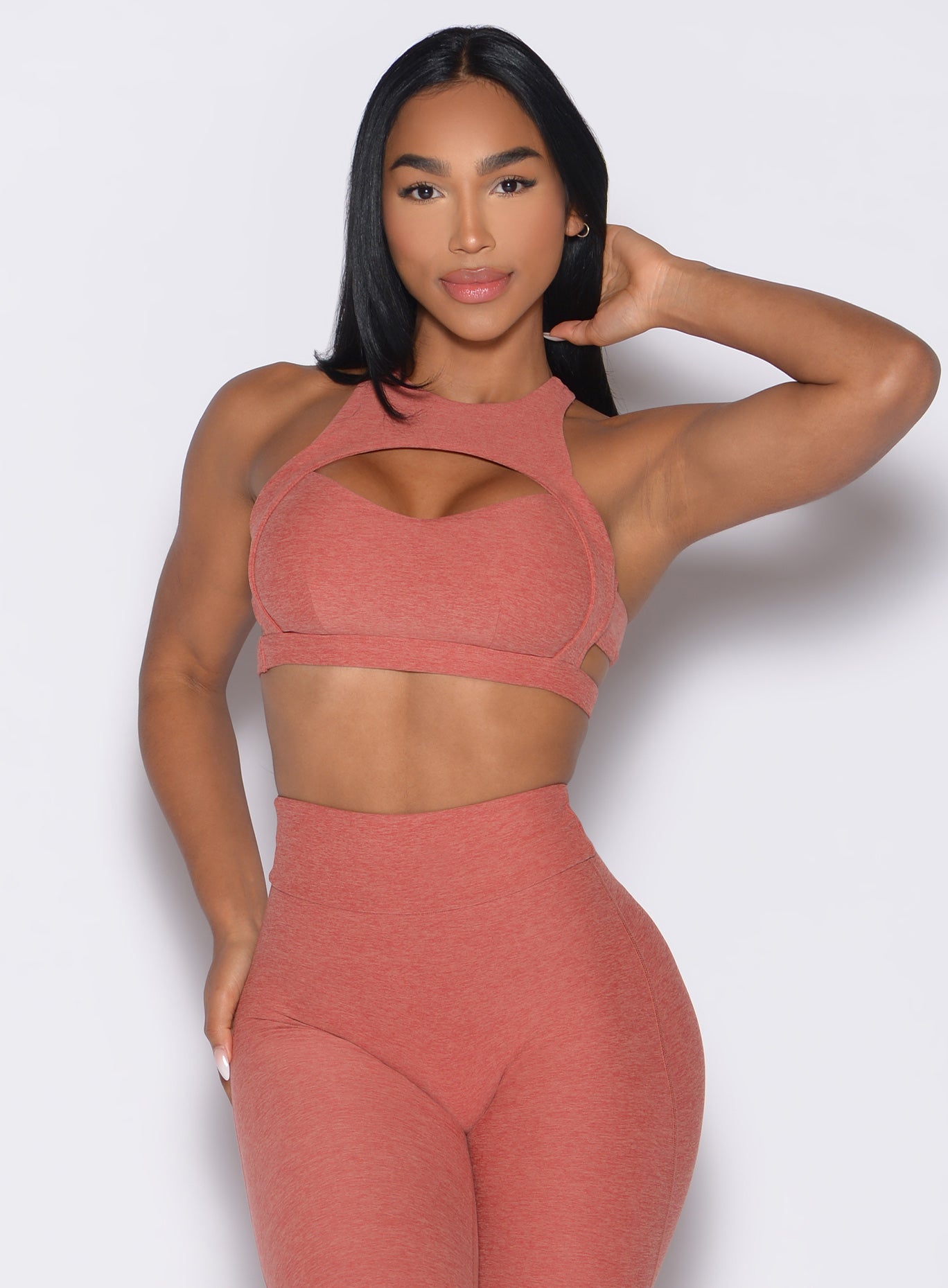 front profile view of a model wearing the Powerhouse bra in Georgia Peach color paired with the matching leggings 