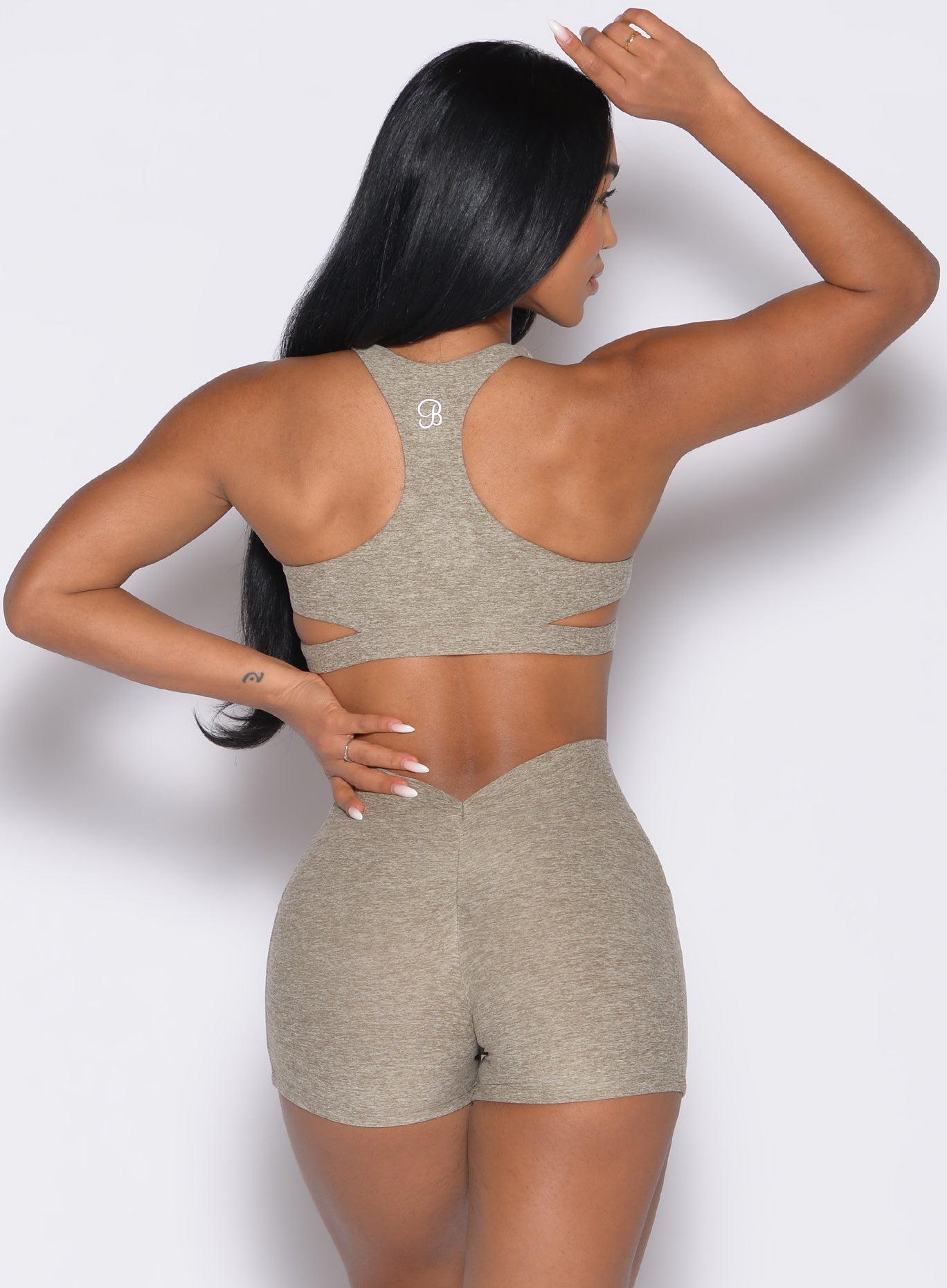 back profile view of a model with one hand on her waist wearing the Powerhouse bra in Toasted Sugar color