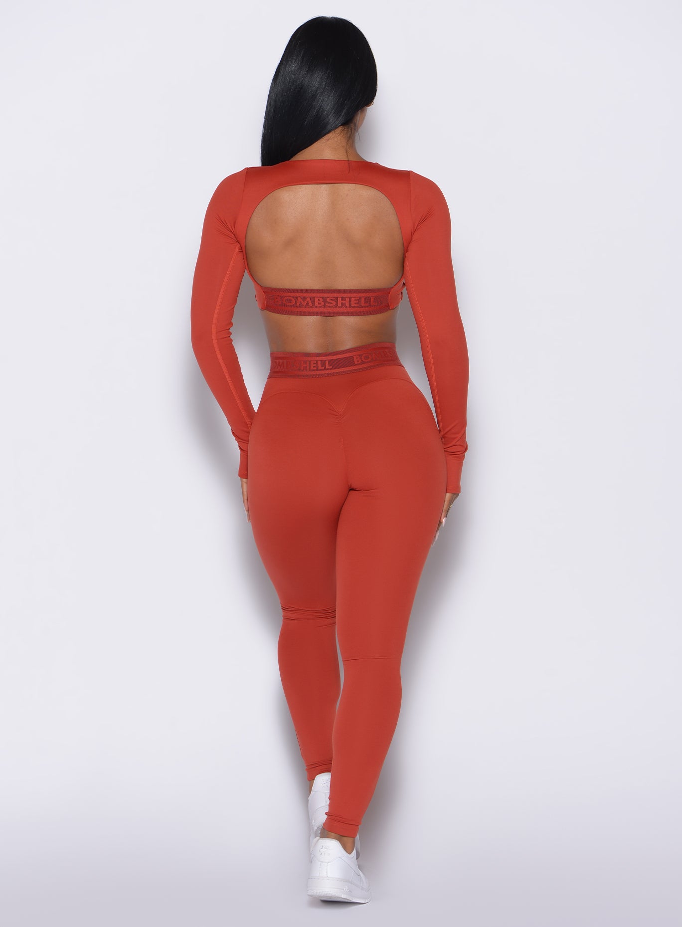 back profile view of our model wearing the Bombshell Active Leggings in red ochre color