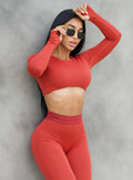 model in outdoors with sunglasses on leaning on a wall wearing the Bombshell Active Pullover in Red Ochre color