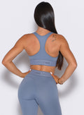 back profile view of our model with both her hands on her waist wearing the Bombshell Active Bra in Flinstone color