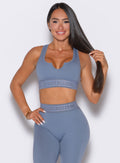 front profile view of our model with one hand on her waist and holding her hair with the other hand wearing the Bombshell Active Bra in Flinstone color