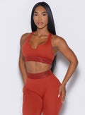 front profile view of our model with both hands resting on her thighs wearing the Bombshell Active Bra in Red Ochre color