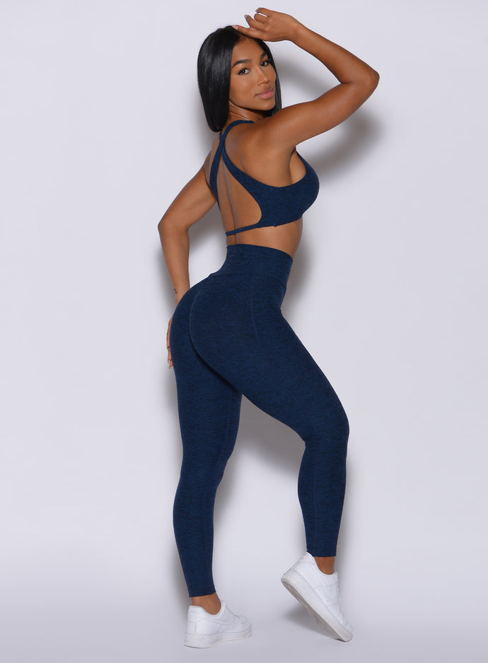 Right  profile view of a model in our Brazilian Contour Leggings in sapphire blue color and a matching ace sports bra