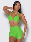 front profile view of a model wearing our butterfly sports bra in neon lime green color along with the matching shorts 