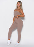 Left side profile view of a model angled slightly to her left wearing our cheeky seamless leggings in Soft Mocha color along with the matching top