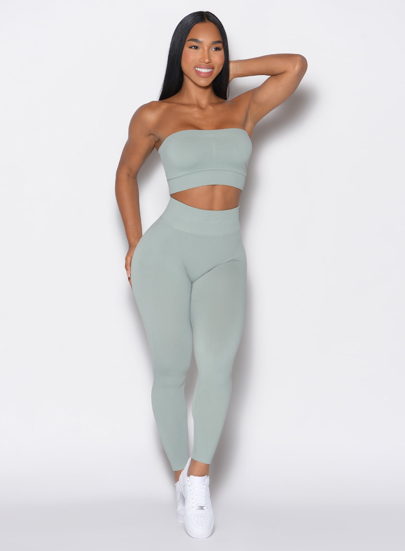 front profile view of a model wearing our cheeky seamless leggings in light jade color along with the matching top