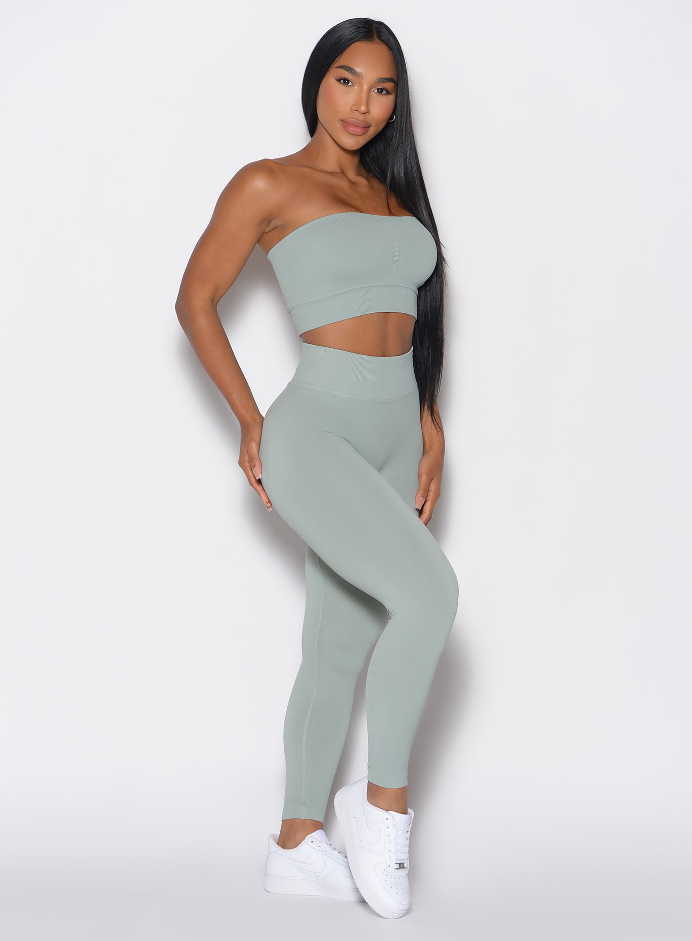 right side profile view of a model angled right wearing our cheeky seamless leggings in light jade color along with the matching top