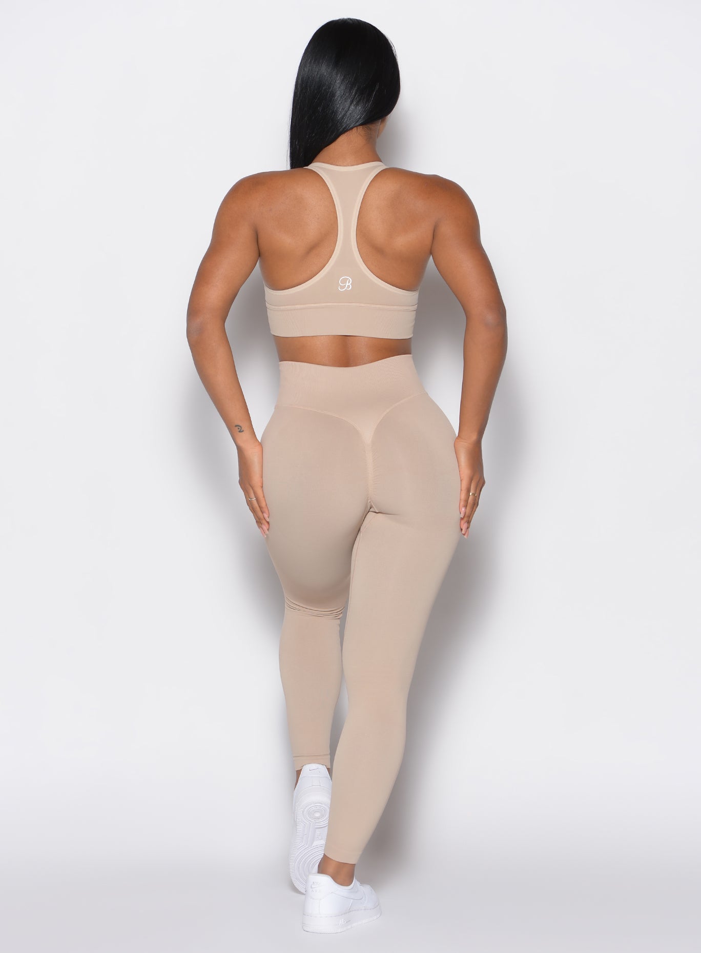back profile view of a model wearing our cheeky seamless leggings in Timeless Taupe color along with the matching sports bra