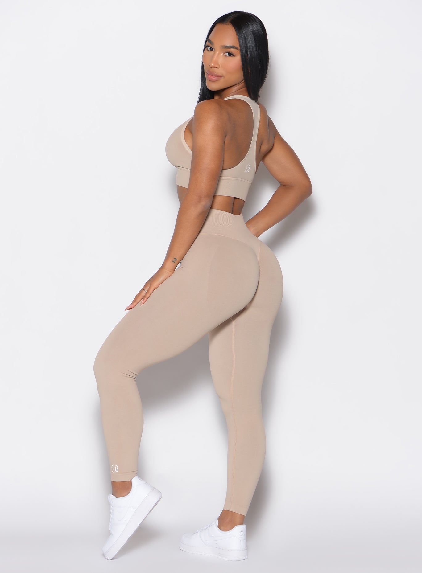 left side profile view of a model wearing our cheeky seamless leggings in Timeless Taupe color along with the matching bombshell bra