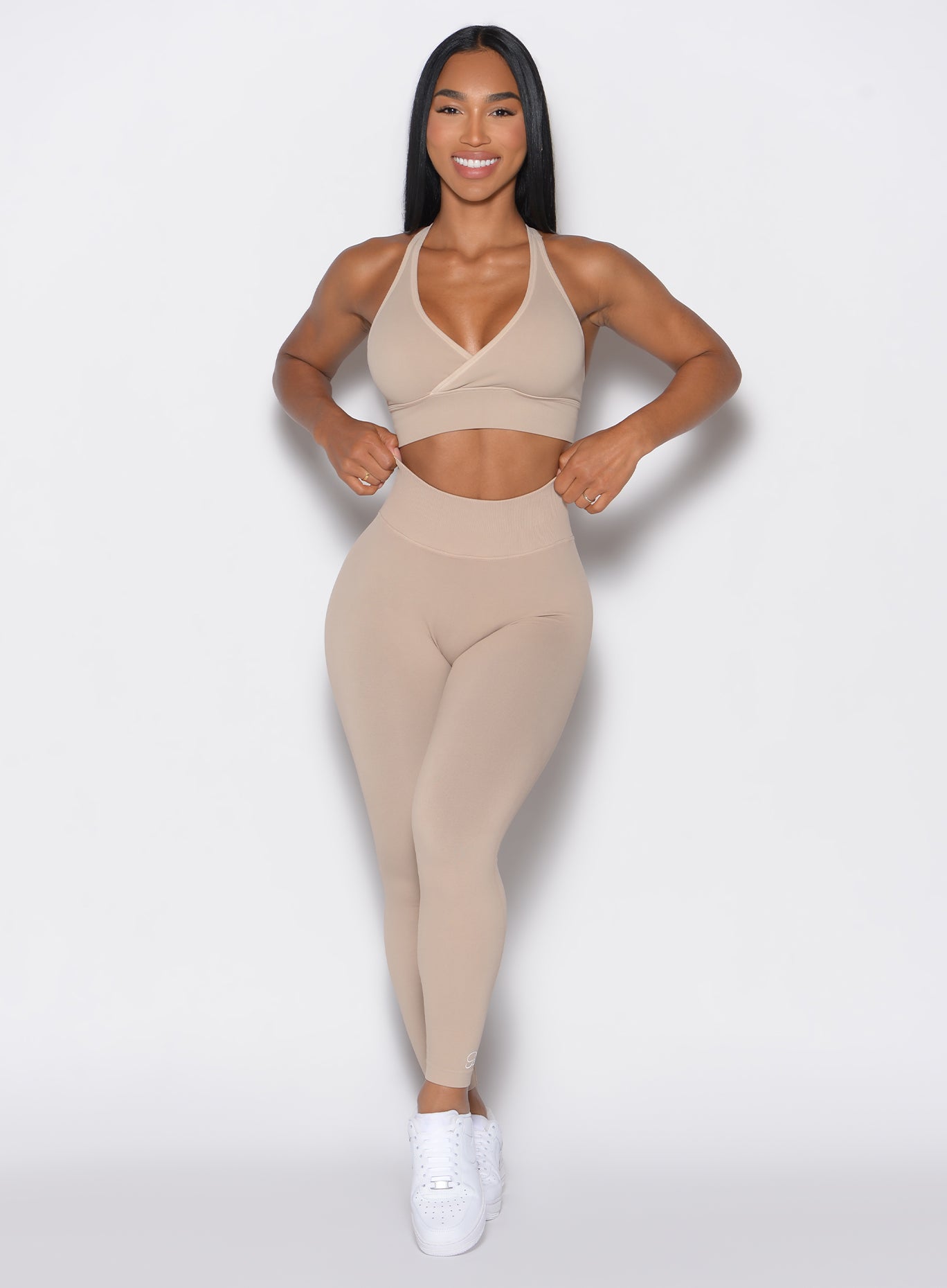 front profile view of a model facing forward  wearing our cheeky seamless leggings in Timeless Taupe color along with the matching sports bra