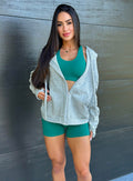 front profile view of a model wearing our heather gray oversized hoodie, along with shorts and a bra in rainforest color standing outside