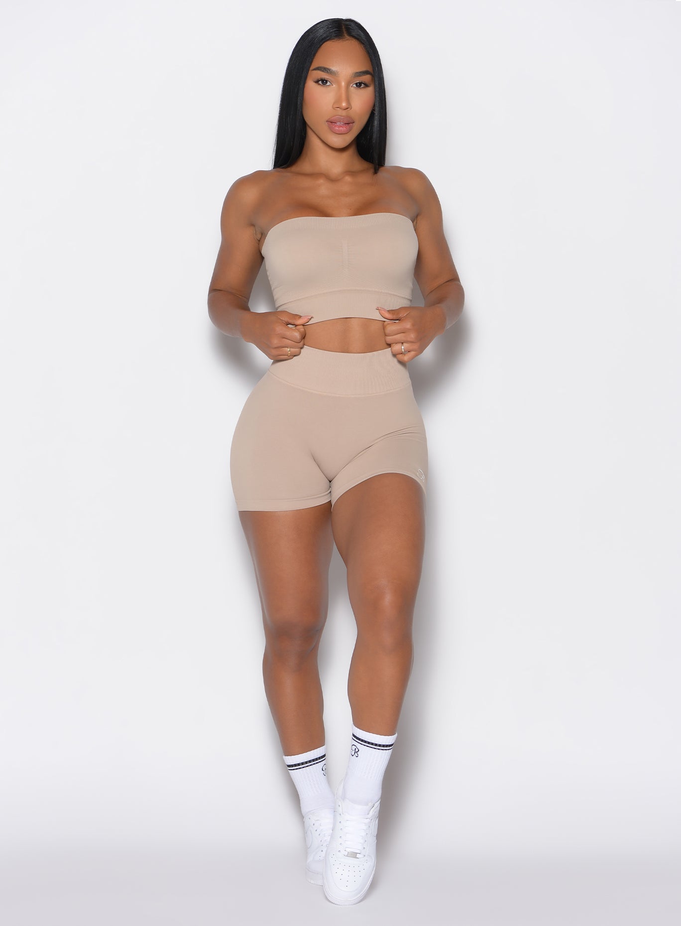 front profile view of a model facing forward wearing our cheeky seamless shorts in timeless taupe color along with a matching bandeau