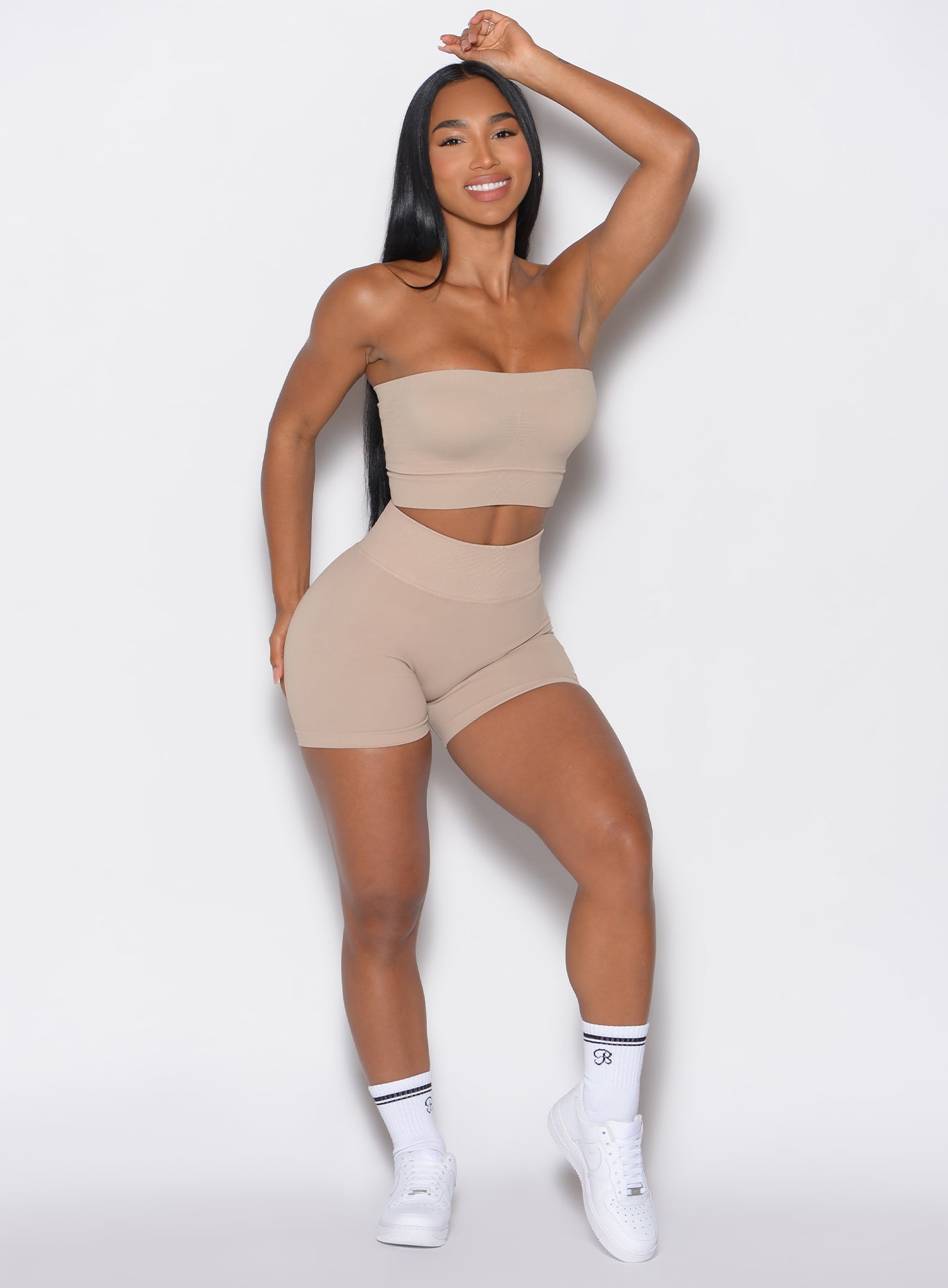 front profile picture of a model facing forward wearing our cheeky seamless shorts in timeless taupe color along with a matching bandeau