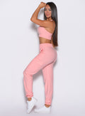 left side profile view of a model with one hand resting on her forehead and looking over her shoulder wearing the Cloud Comfort Joggers in Peachy pink color