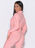 left side profile view of a model looking over her shoulder wearing the Cloud Full Length Jacket in Peachy pink color