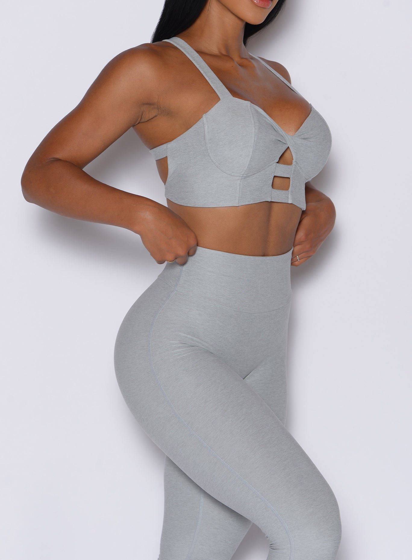 right side profile view of a model wearing our core set bra in light cloud color along with the matching leggings