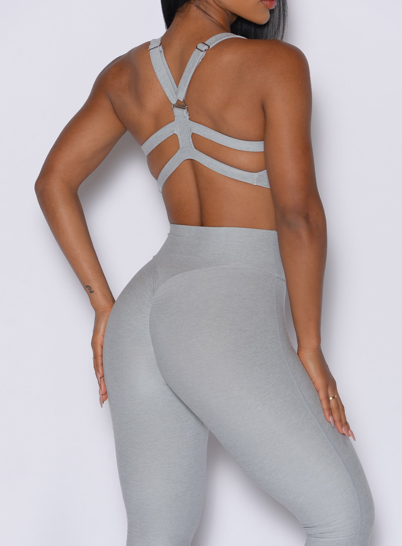 back profile view of a model wearing our core set bra in light cloud color along with the matching leggings