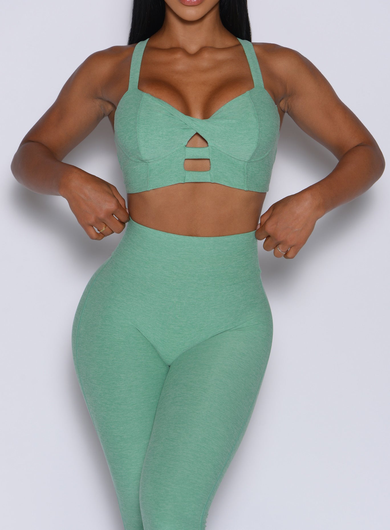 front profile view of a model wearing our core set bra in sage color along with the matching leggings