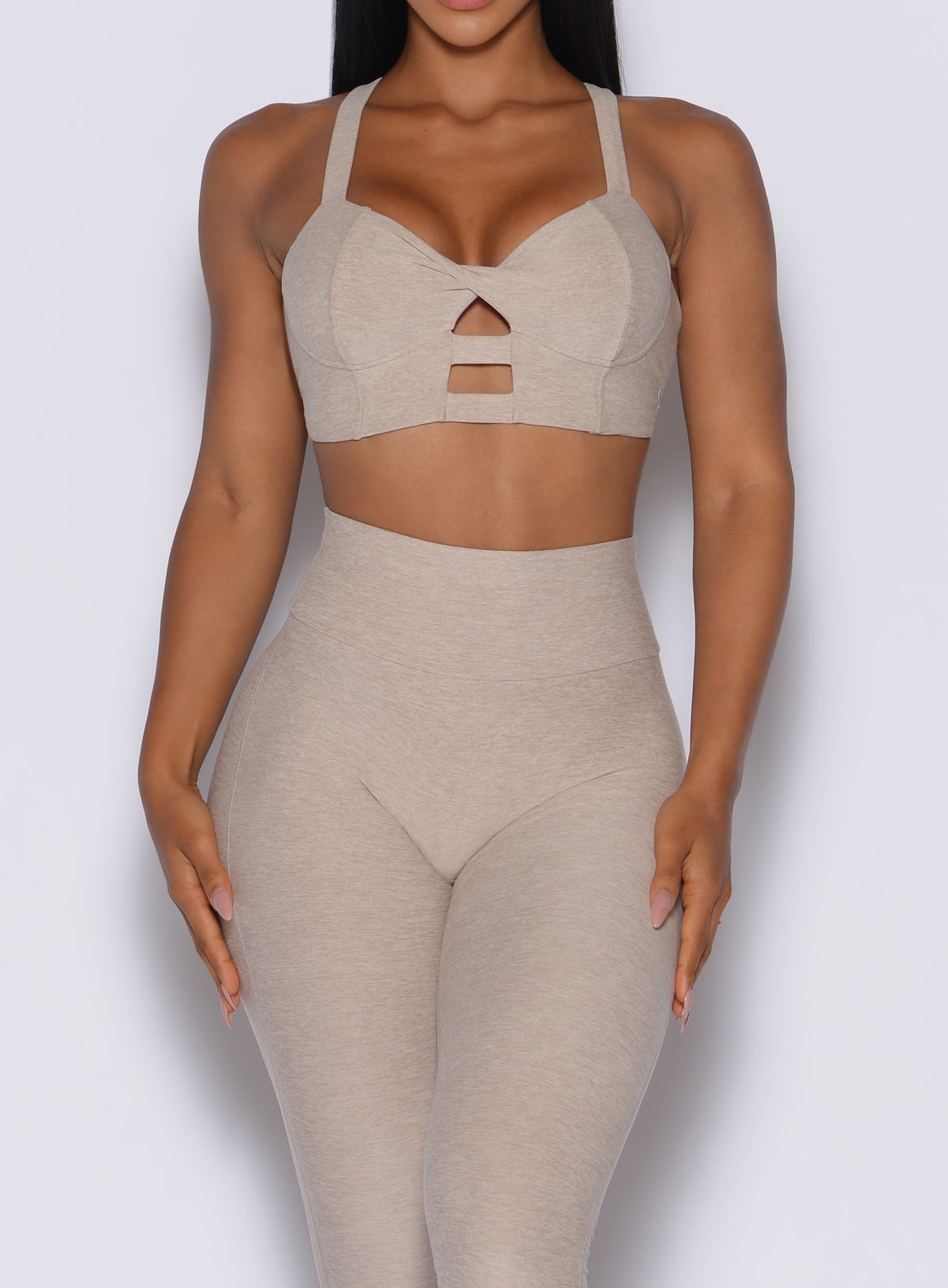 front profile view of a model wearing our core set bra in taupe color along with the matching leggings