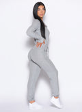 right side profile view of a model with one hand on her waist wearing the Flirty Jumpsuit in Cozy silver color